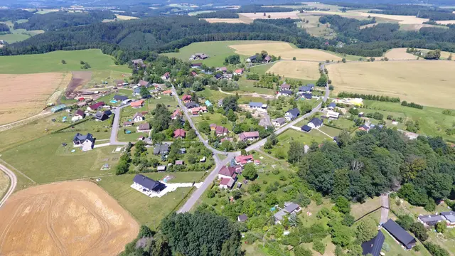 Jivina shora: silnice obcí, domy se zahradami, vpravo les