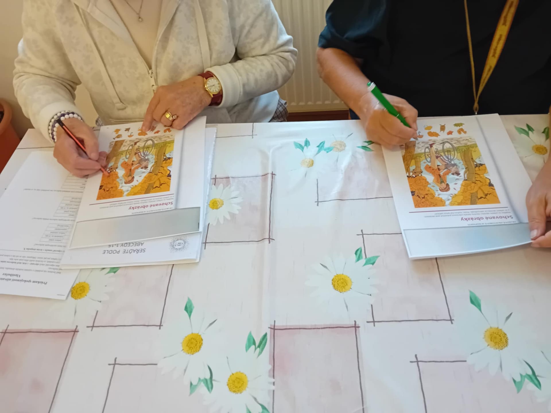Ruce dvou účastnic vyplňují pracovní listy s úlohami