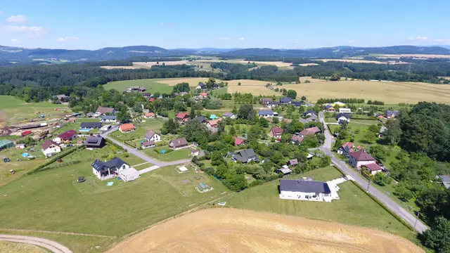 Jivina shora: zástavba podél silnice, vlevo dole sklizené pole, vpravo les
