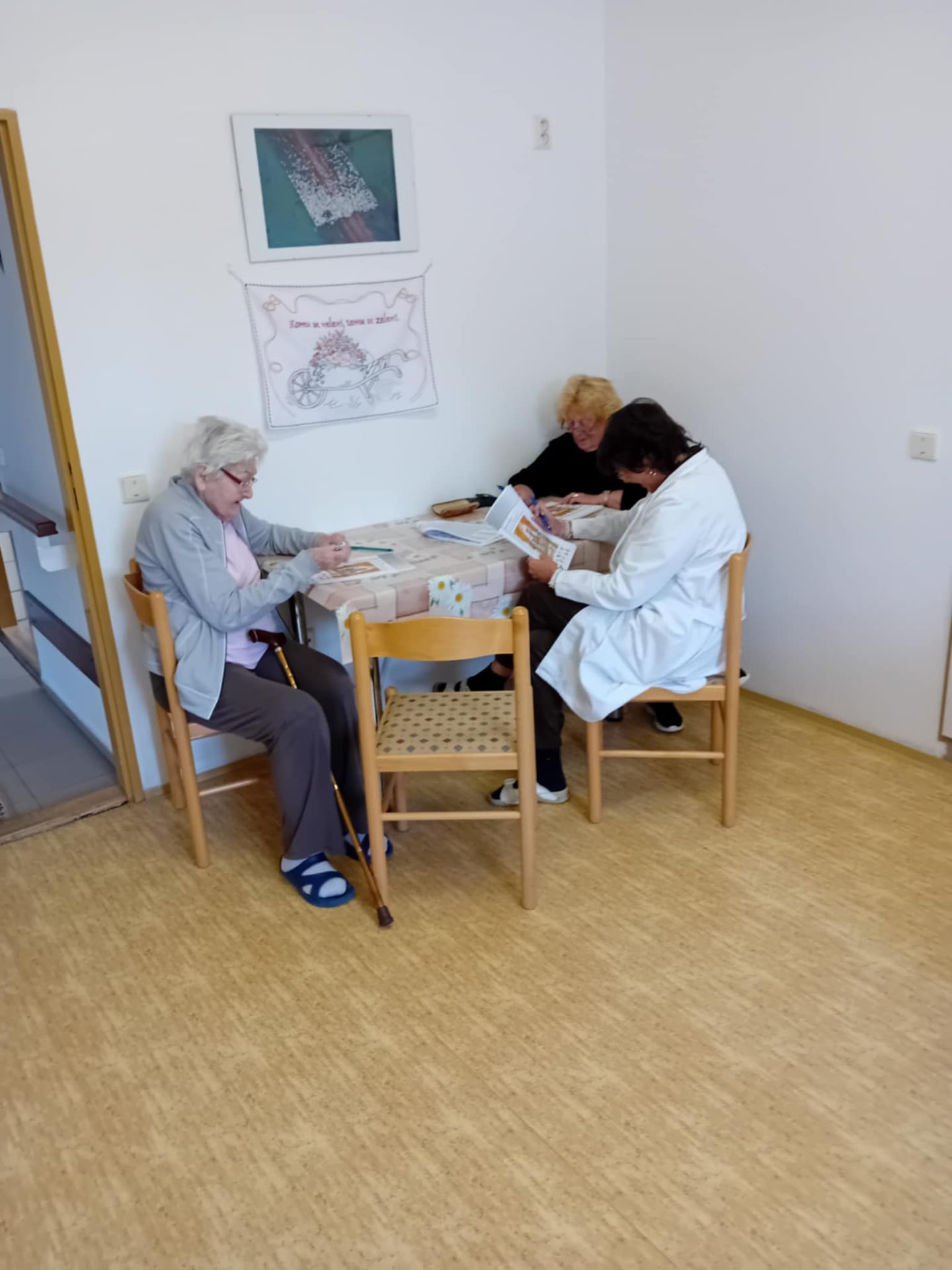 Tři účastnice řeší úlohy u stolu v rohu místnosti