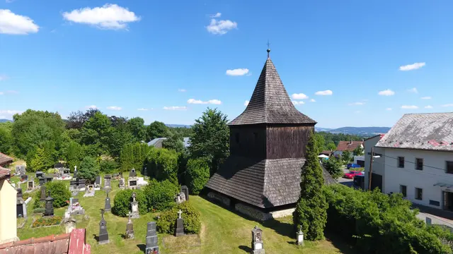 Dřevěná zvonice se šindelovou střechou vedle hřbitova